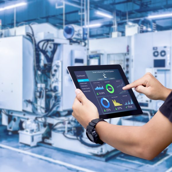 Smart industry control concept. Hands holding tablet on blurred automation machine as background